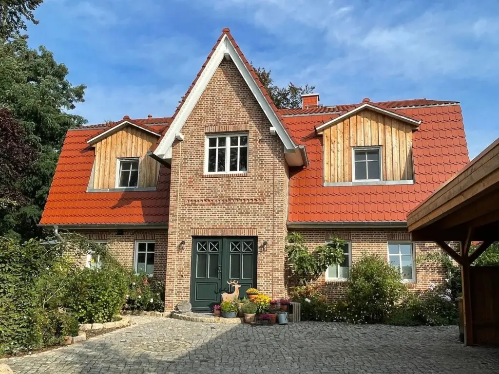 Wohnhaus mit Klinkerfassade, Holzelementen und rotem Dach