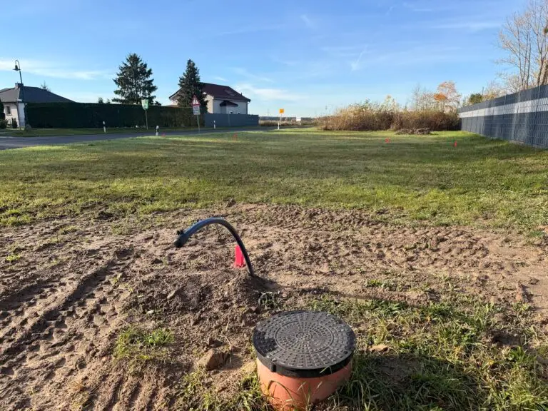 Unbebautes Baugrundstück mit Schachtdeckel des Hausanschlusses